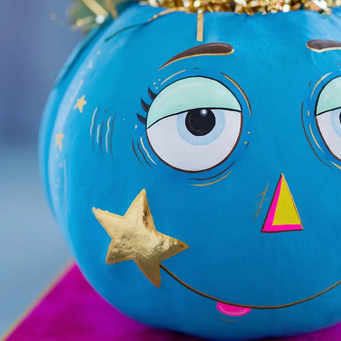 Glitterville Hugourd Pumpkin Pixie Bucket in bright blue with large expressive eyes, gold star accents, pink details, and an open top with a wire handle.
