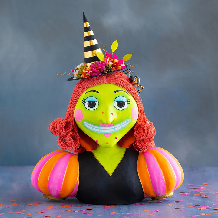 Glitterville Itchy Witchy Bust display Halloween decoration featuring a whimsical lime-green witch with bright red curled hair, a black and gold striped pointed hat decorated with colorful flowers, pink and orange striped sleeves, and a playful spooky smile.