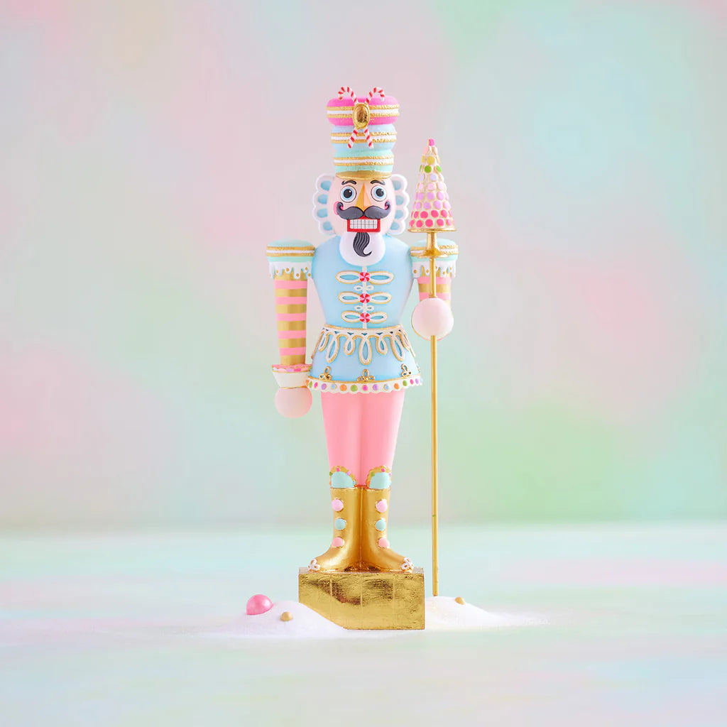 Glitterville pastel nutcracker display figure wearing a colorful macaron-inspired hat and tree topper staff, decorated in light blue, pink, white, and gold with candy-inspired details.