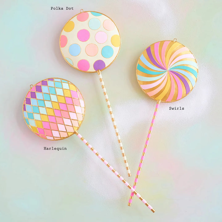 Glitterville pastel Licky Lollipop display set featuring three whimsical oversized lollipops with colorful polka dots, rainbow swirls, pastel pink, blue, yellow, and lavender patterns, and gold accents. Pattern labeled are displayed for easy distinguishing. 