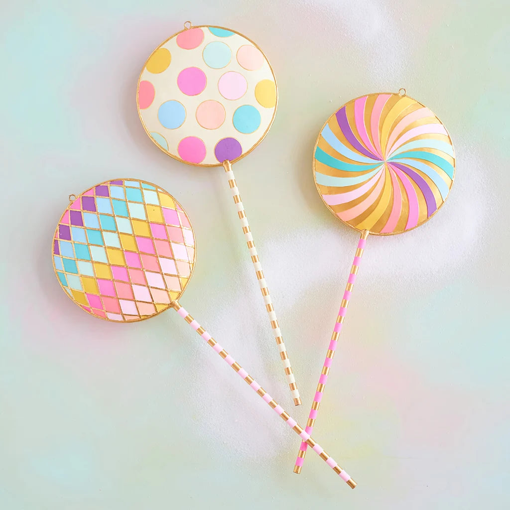 Glitterville pastel Licky Lollipop display set featuring three whimsical oversized lollipops with colorful polka dots, rainbow swirls, pastel pink, blue, yellow, and lavender patterns, and gold accents.