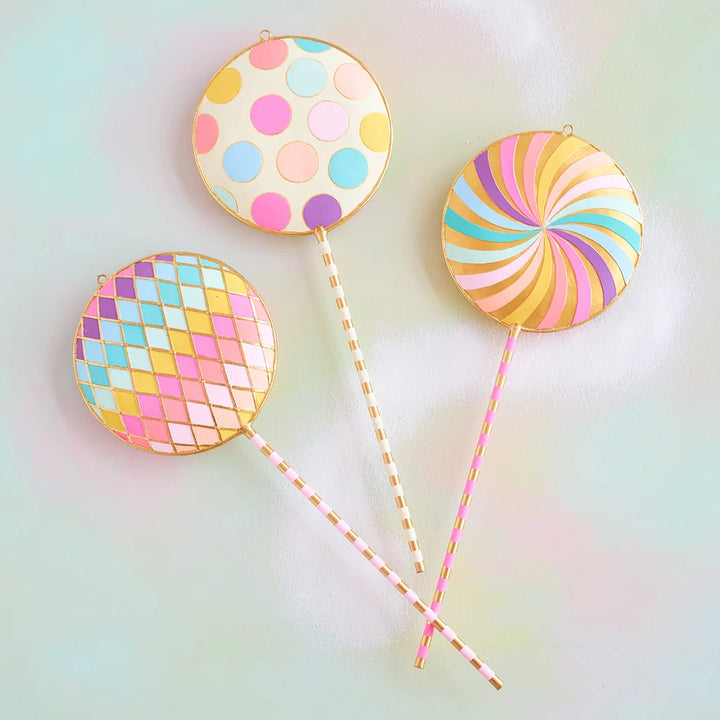 Glitterville pastel Licky Lollipop display set featuring three whimsical oversized lollipops with colorful polka dots, rainbow swirls, pastel pink, blue, yellow, and lavender patterns, and gold accents.