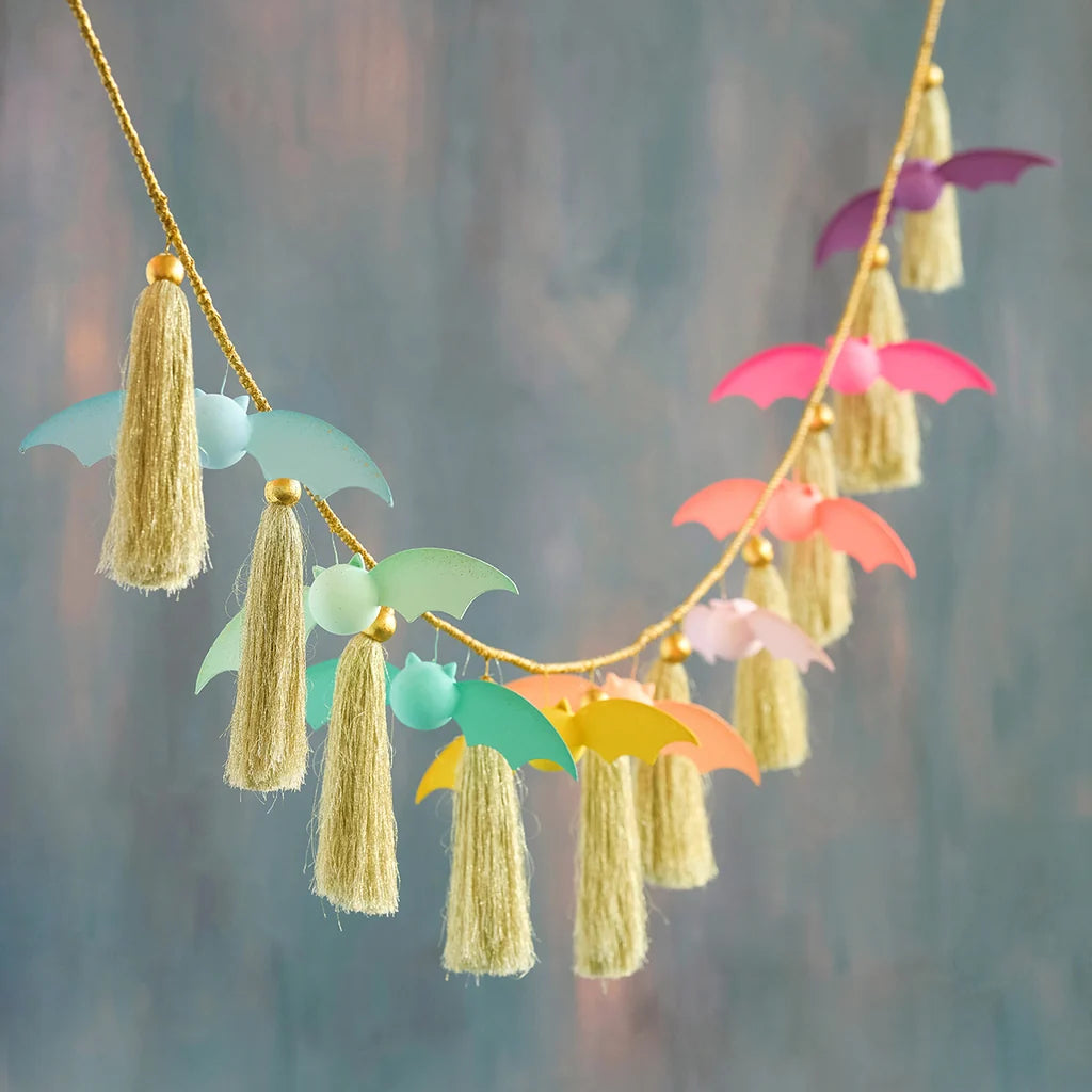 Glitterville pastel Rainbow Bat garland featuring colorful pink, purple, peach, mint, teal, yellow, and blue bat decorations paired with shimmering gold tassels on a gold cord.