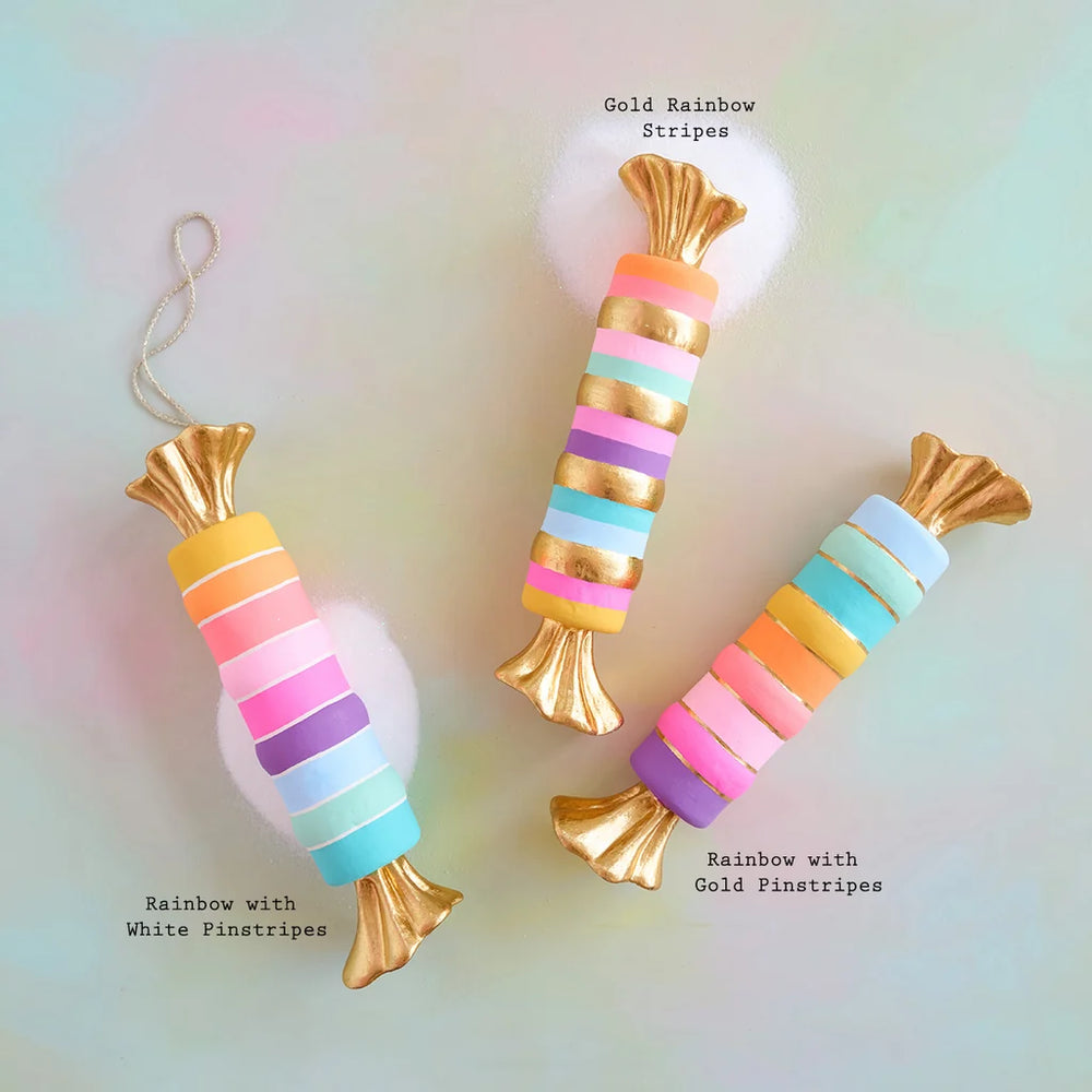 Glitterville pastel Rainbow Taffy display set featuring three whimsical oversized wrapped candies in colorful pink, purple, blue, yellow, and mint stripes with shimmering metallic gold wrappers and accents. Color pattern sequences labeled for easy distinguishing. 