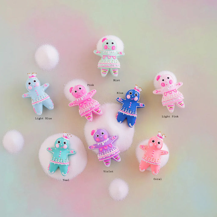 Rainbow multicolor Glitterville Dippsy and Dough gingerbread figure ornaments arranged on a soft pastel background, with each figure labeled by color: Light Blue, Mint, Pink, Blue, Teal, Violet, Hot Pink, and Coral. The figures feature detailed white and pink icing, gold accents, and whimsical gumdrop headpieces.
