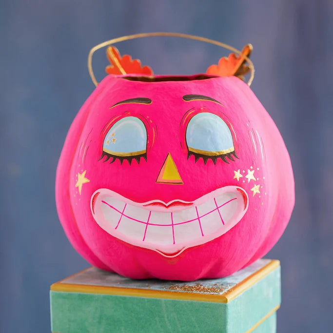 Glitterville Squinkie Pumpkin Pixie Bucket in bright pink with a smiling face, closed eyes, star details, and orange pumpkin stem accents.