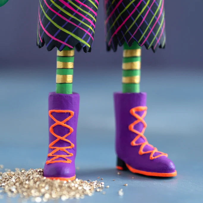 Close-up of the hand-painted Glitterville Swanky Franky Halloween ornament legs and boots, featuring green-and-gold striped legs, colorful plaid pants, and purple boots with bright orange laces and soles.