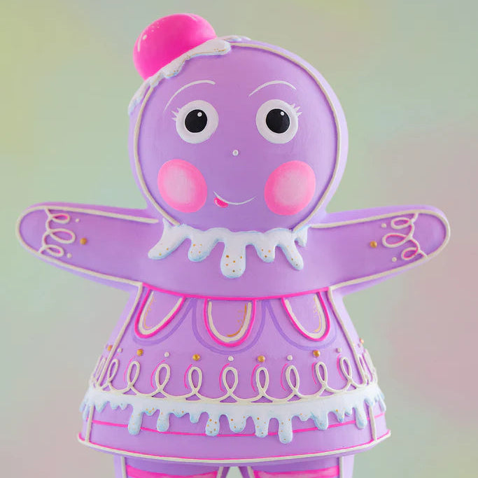 Close-up of the Glitterville Violet Dippsey gingerbread figure showcasing intricate pink, white, and gold icing details, including looping piped icing, decorative gold sugar accents, dripping white icing trim, rosy pink cheeks, expressive piped facial details, and a bright pink gumdrop headpiece. This detailed view highlights the whimsical handcrafted-style decoration and pastel Christmas design of the Glitterville gingerbread collectible.