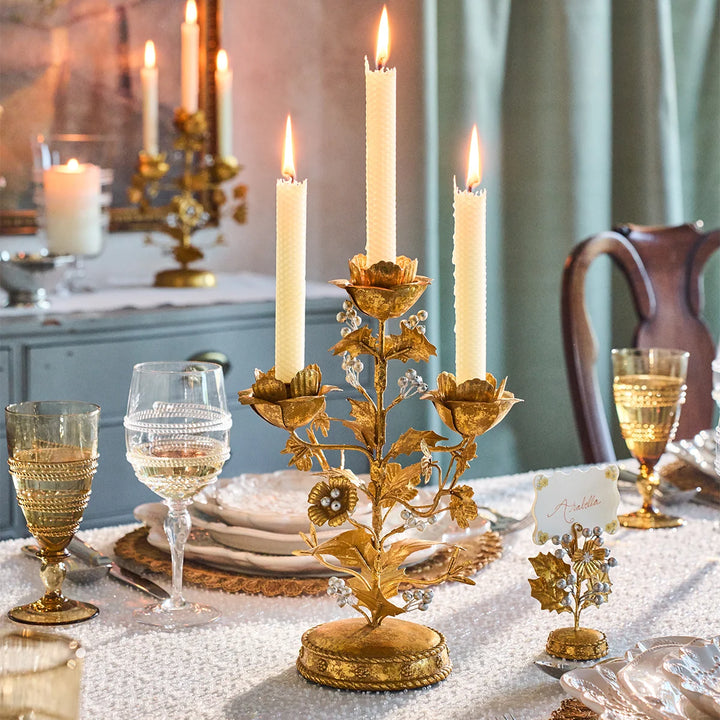 Gold Holly 3-Light Candelabra with three lit white taper candles styled on an elegant Christmas dining table