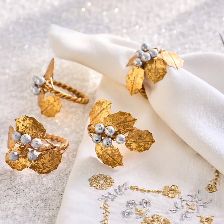 Gold Holly Napkin Rings with metallic gold leaves and silver berries styled with elegant white holiday linens