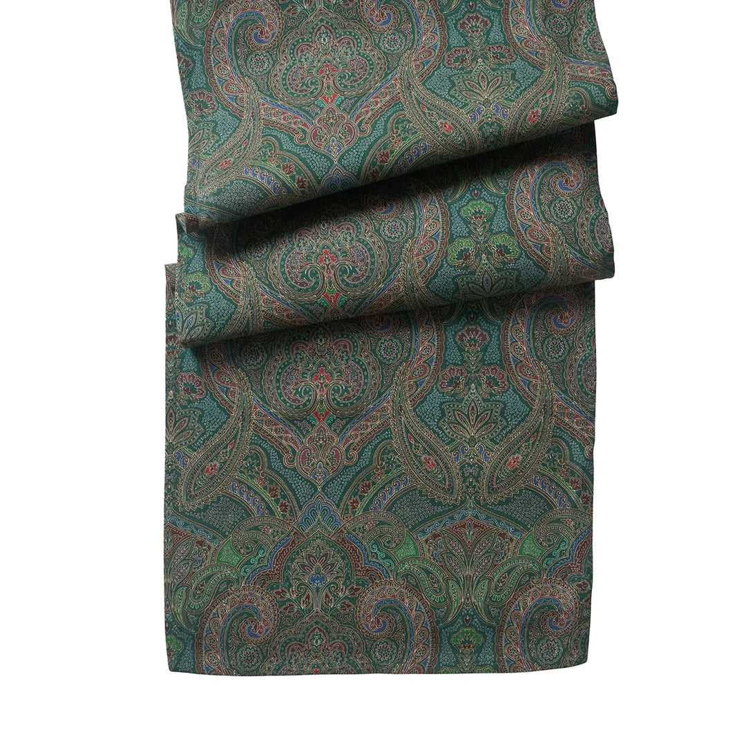 Green paisley table runner featuring an intricate jewel-tone pattern with floral and scroll details in burgundy, blue, brown and green.
