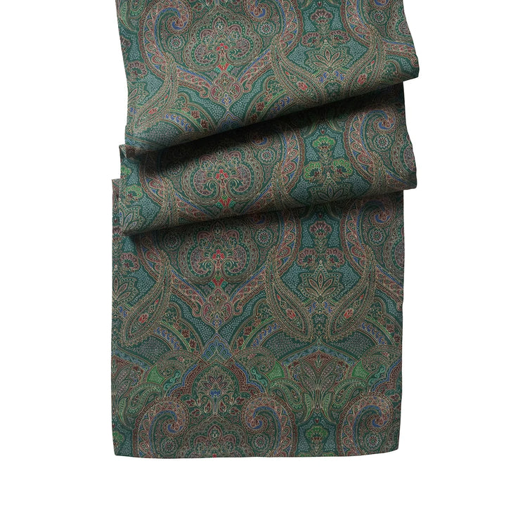 Green paisley table runner featuring an intricate jewel-tone pattern with floral and scroll details in burgundy, blue, brown and green.