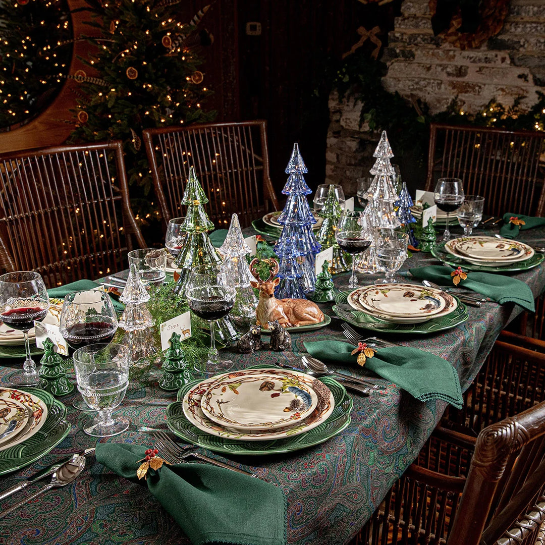 Green paisley tablecloth styled for Christmas with green dinnerware, botanical plates, glass trees and coordinating green napkins.