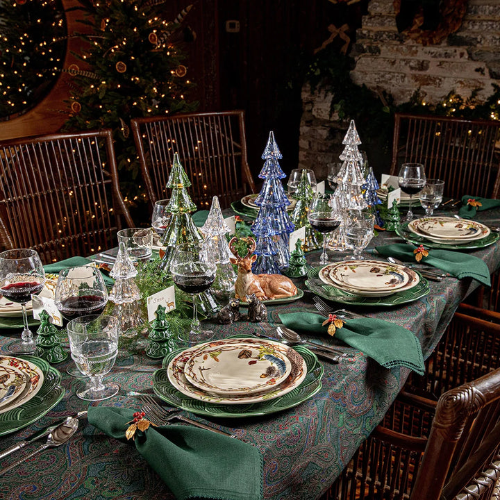 Green paisley tablecloth styled for Christmas with green dinnerware, botanical plates, glass trees and coordinating green napkins.