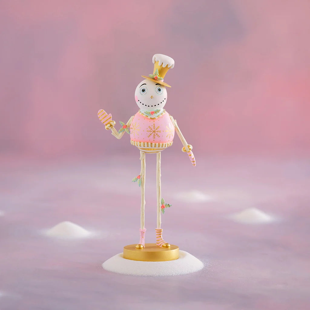 Holly Jolly tabletop display featuring a whimsical snowman ornament in a pink sweater and chef-style hat, holding a striped candy cane, with gold and pastel accents against a soft pink snowy backdrop.
