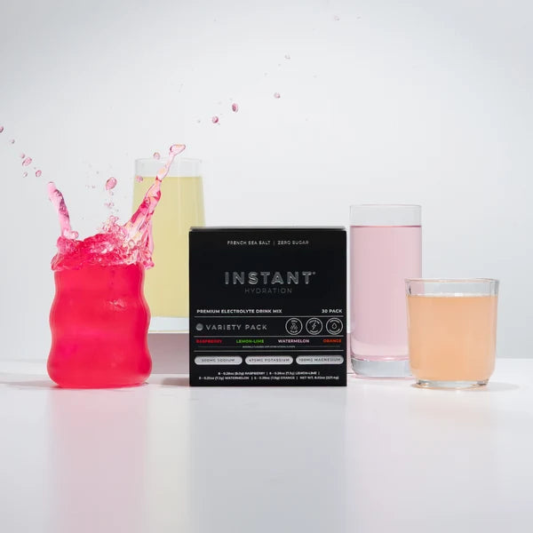 Instant Hydration electrolyte drink mix variety pack displayed with prepared Raspberry, Lemon-Lime, Watermelon and Orange hydration drinks.
