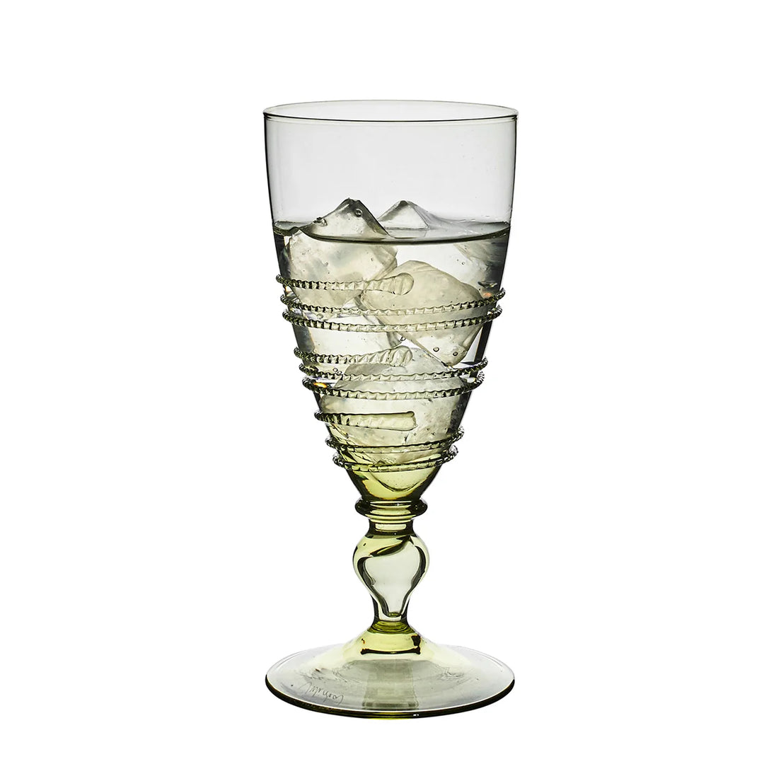 Juliska Amalia green footed goblet filled with ice, featuring pale green glass, a decorative stem and signature wrapped thread detailing.