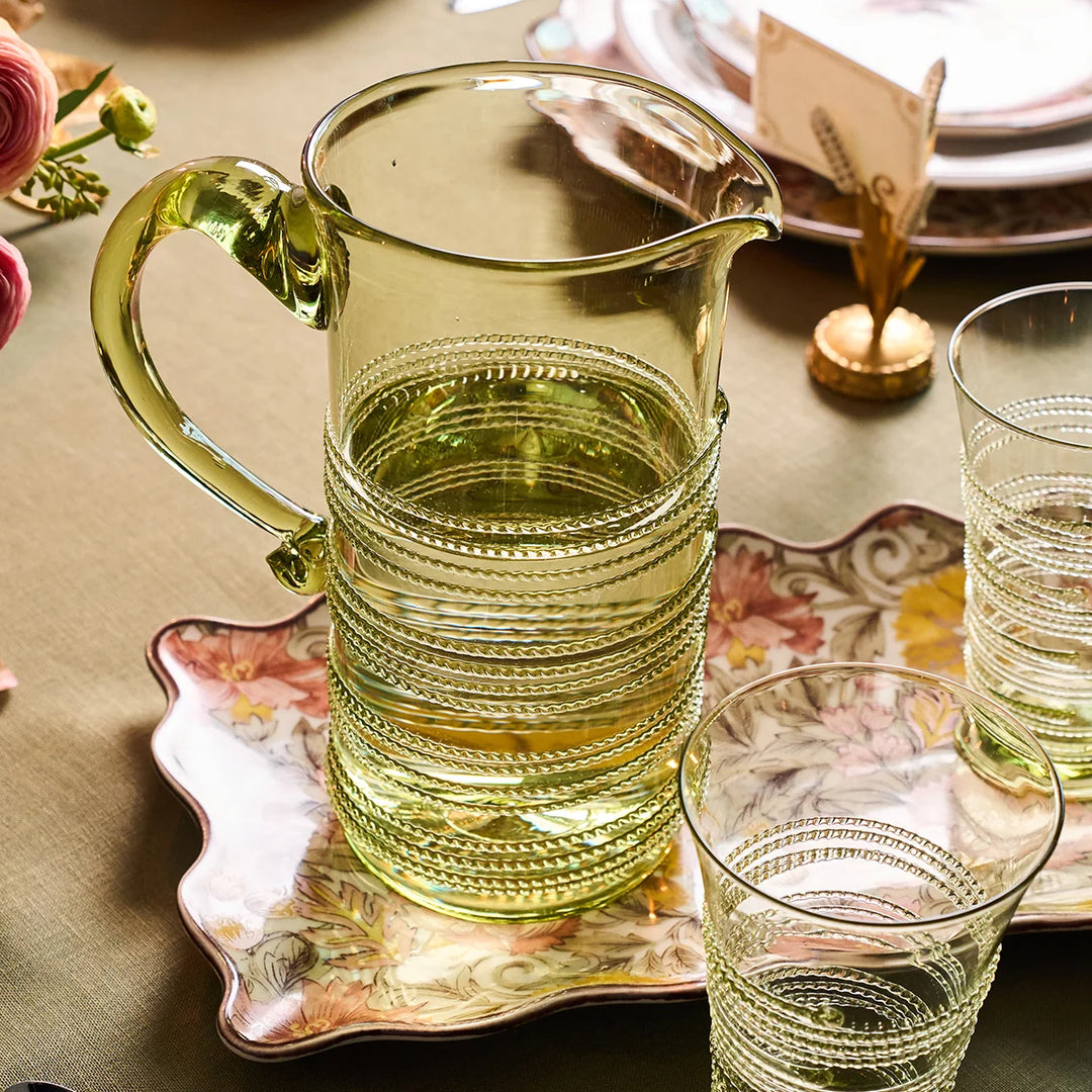 Juliska Amalia Green Pitcher styled on an elegant floral tablescape with coordinating green drinking glasses and dinnerware.