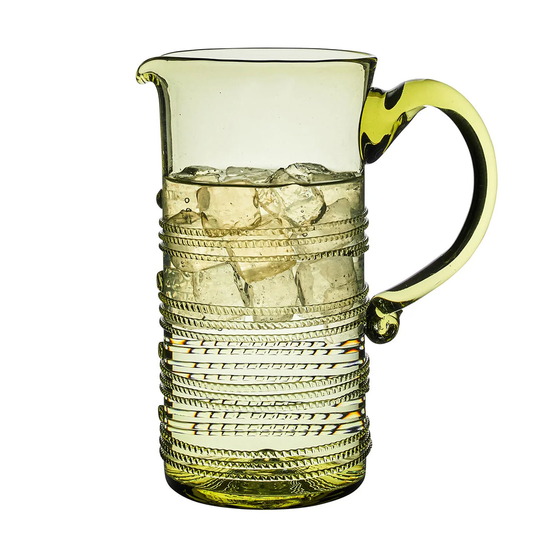 Juliska Amalia Green Pitcher filled with ice, featuring a pale green glass finish, curved handle and decorative thread detailing.
