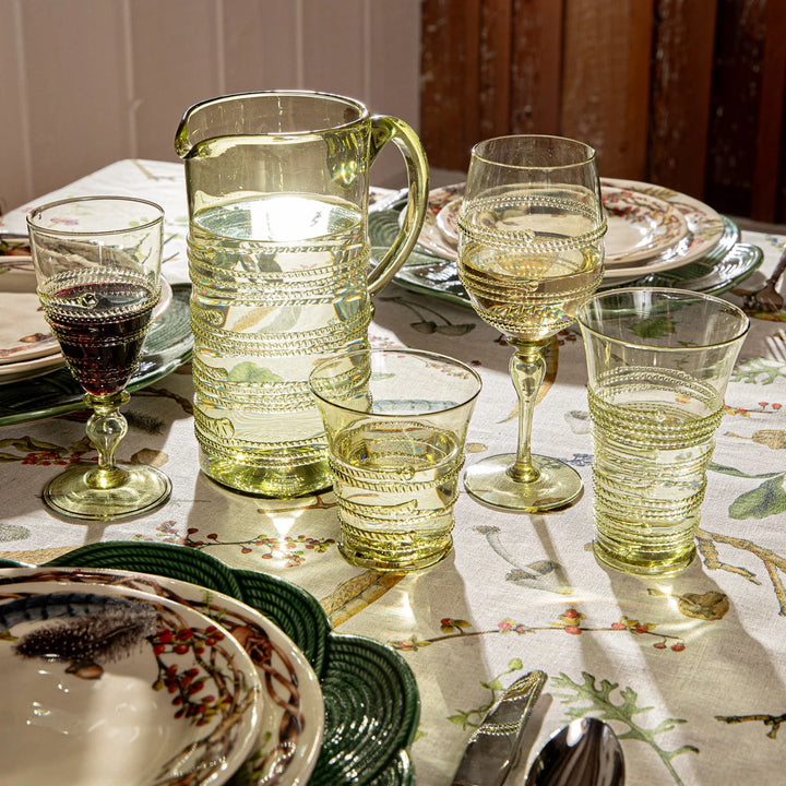 Juliska green glass highball drinking glasses displayed with coordinating pitcher, wine glasses and tableware on a botanical tablescape.