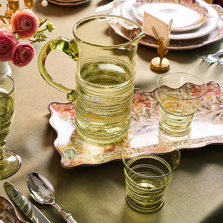 Juliska green glass tumblers styled with a coordinating green glass pitcher on an elegant floral tablescape for entertaining.
