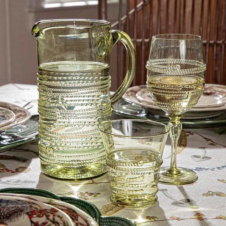 Juliska green glass tumbler styled with a coordinating pitcher and wine glass on an elegant botanical tablescape.