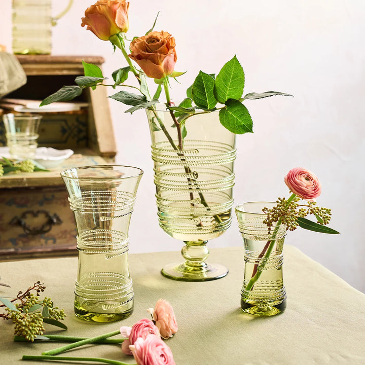 Juliska green glass vase styled with flowers alongside coordinating green glass vases for an elegant floral display.