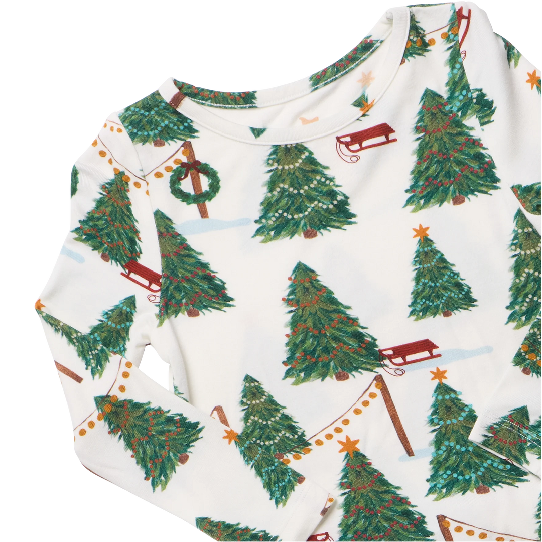 Close-up of Christmas Tree Farm bamboo pajamas featuring decorated evergreen trees, red sleds, and festive holiday garlands.