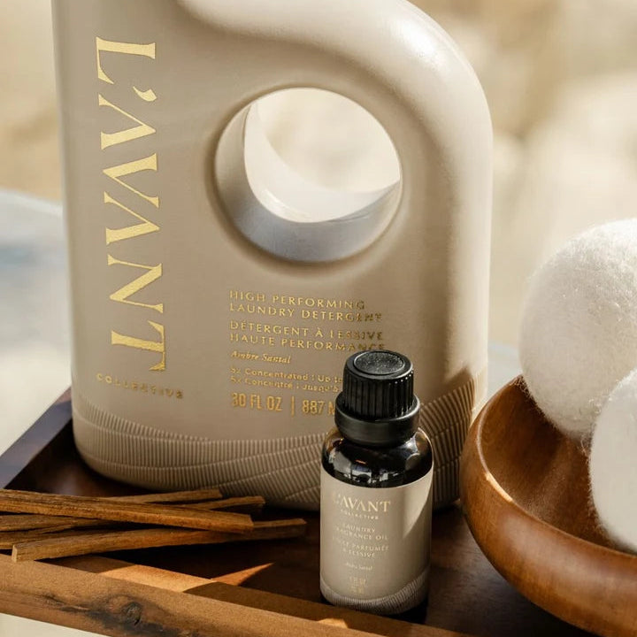 L’AVANT Collective Ambre Santal laundry detergent and Laundry Fragrance Oil styled with wool dryer balls and wood accents.