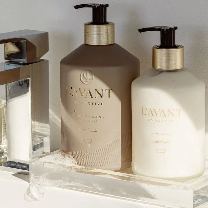 L’AVANT Collective Ambre Santal Hand Lotion and High Performing Hand Soap displayed together beside a modern bathroom sink