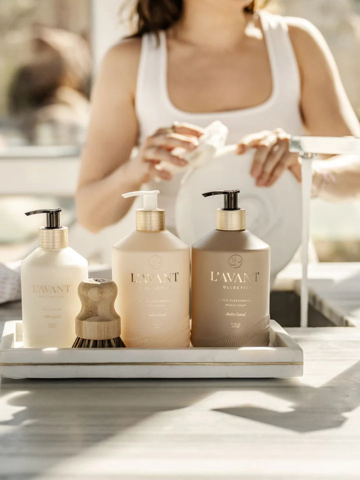 L’AVANT Collective Ambre Santal Hand Lotion styled with matching hand soap and dish soap on a kitchen sink tray