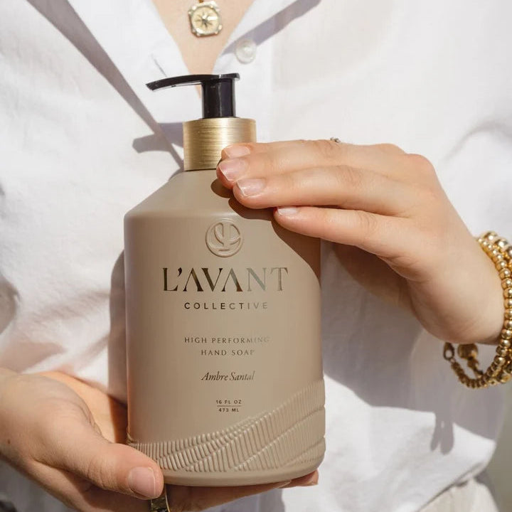 L’AVANT Collective Ambre Santal High Performing Hand Soap 16 oz bottle held in hand, featuring taupe and gold packaging