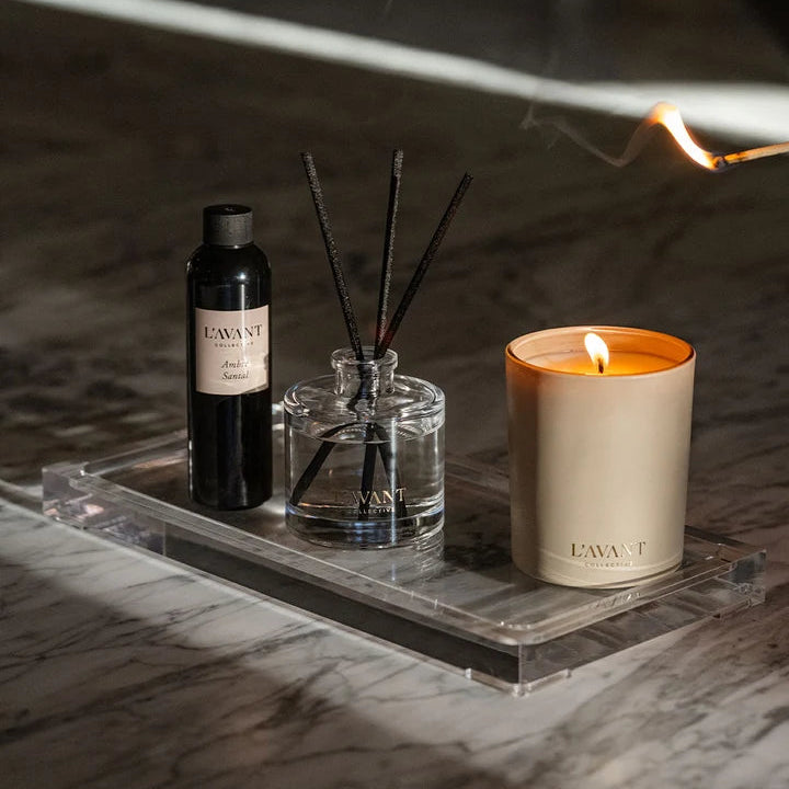 L’AVANT Collective Ambre Santal candle, reed diffuser and diffuser refill styled together on a clear tray.