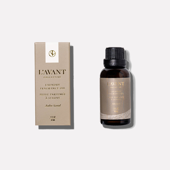 L’AVANT Collective Ambre Santal Laundry Fragrance Oil in an amber glass bottle displayed beside its product box.