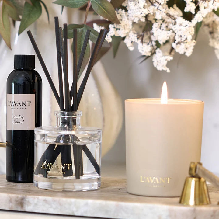 L’AVANT Collective Ambre Santal reed diffuser with refill oil and scented candle styled with fresh flowers.