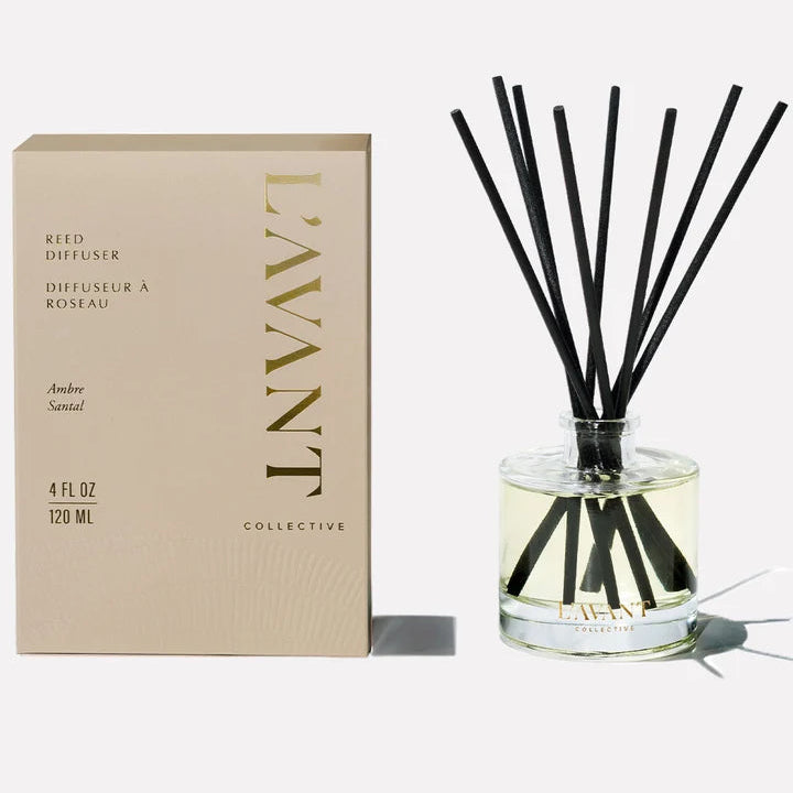 L’AVANT Collective Ambre Santal reed diffuser with clear glass vessel, black reeds and coordinating product box.