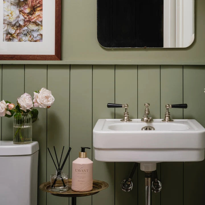 L’AVANT Collective Blushed Bergamot reed diffuser and hand lotion styled beside a bathroom sink.
