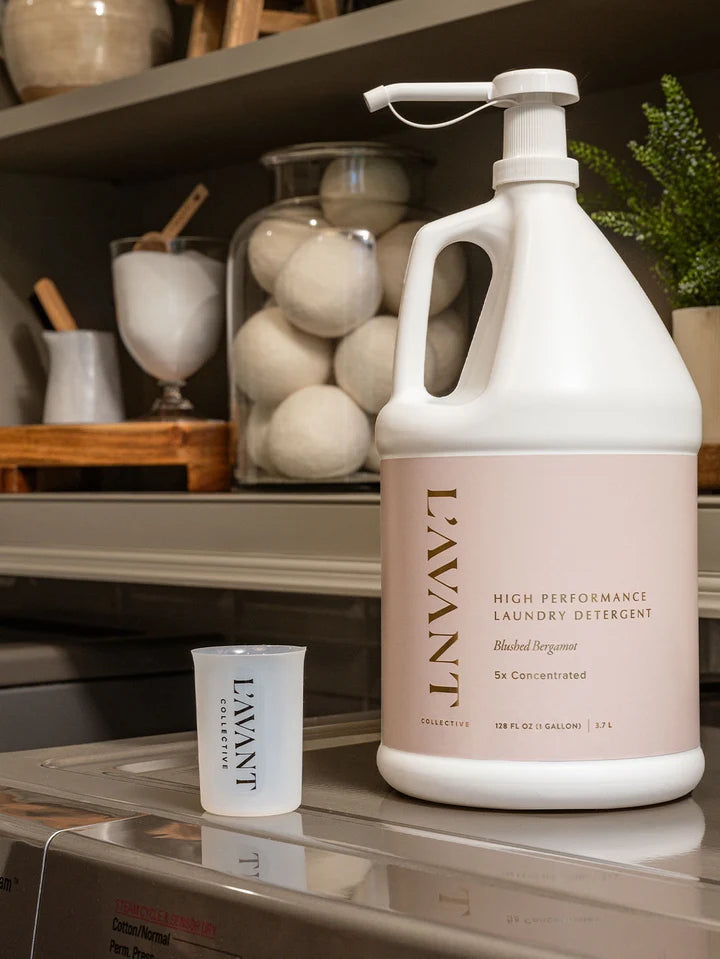 L’AVANT Collective Blushed Bergamot gallon laundry detergent with measuring cup in laundry room