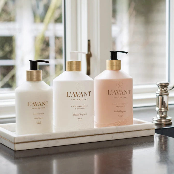 L’AVANT Collective Blushed Bergamot Hand Lotion styled with matching hand soap and dish soap on a kitchen sink tray