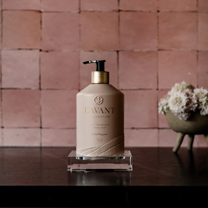 L’AVANT Blushed Bergamot High Performing Hand Soap displayed on a clear tray against a blush pink tile wall