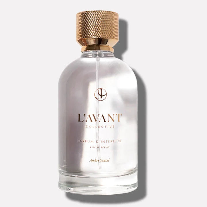 L’AVANT Collective Ambre Santal Parfum d’Intérieur Room Spray in a clear glass bottle with a textured gold cap.
