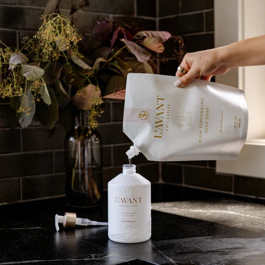 L’AVANT Dish Soap Refill being poured into a reusable dish soap bottle on a kitchen counter
