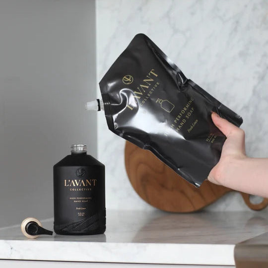L’AVANT Fresh Linen High Performing Hand Soap Refill pouch shown refilling a black hand soap pump bottle