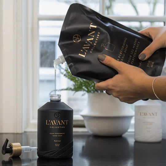L’AVANT Fresh Linen High Performing Hand Soap Refill being poured into a black hand soap bottle