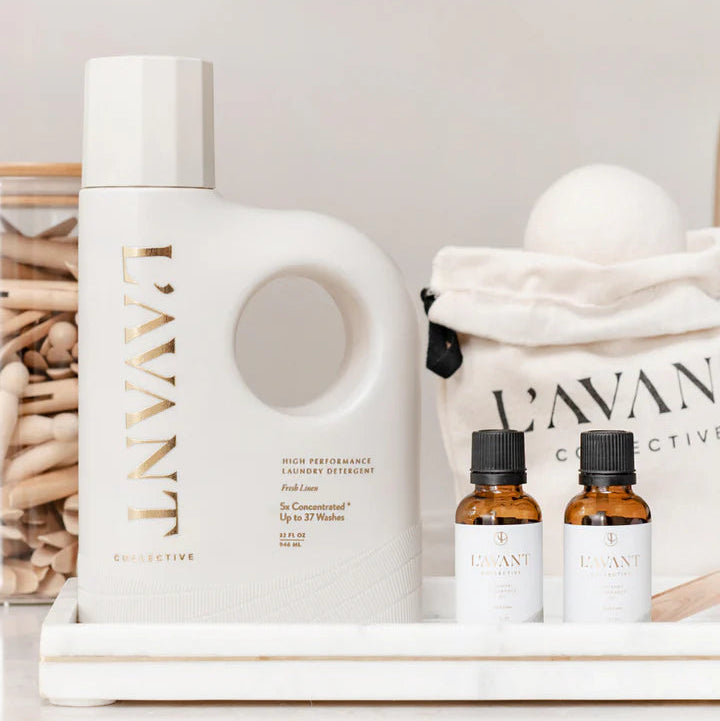 L’AVANT Collective Fresh Linen laundry detergent displayed with laundry fragrance oils and laundry accessories
