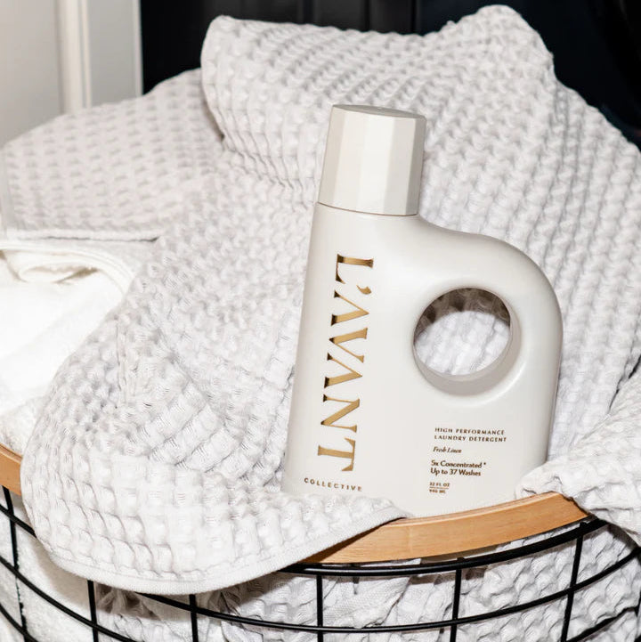 L’AVANT Collective Fresh Linen Laundry Detergent displayed in a basket of clean white linens