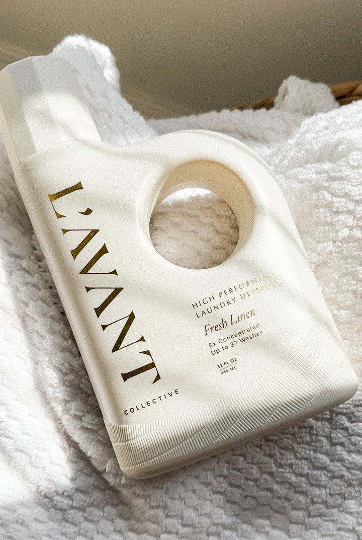 L’AVANT Collective Fresh Linen Laundry Detergent 32 oz bottle displayed on soft white linens
