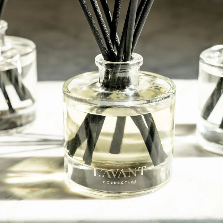 L’AVANT Collective Fresh Linen luxury reed diffuser with black fragrance reeds displayed on a marble countertop.