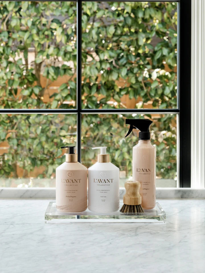 L’AVANT Collective hand soap, dish soap and multipurpose cleaner displayed with a dish brush on a kitchen counter