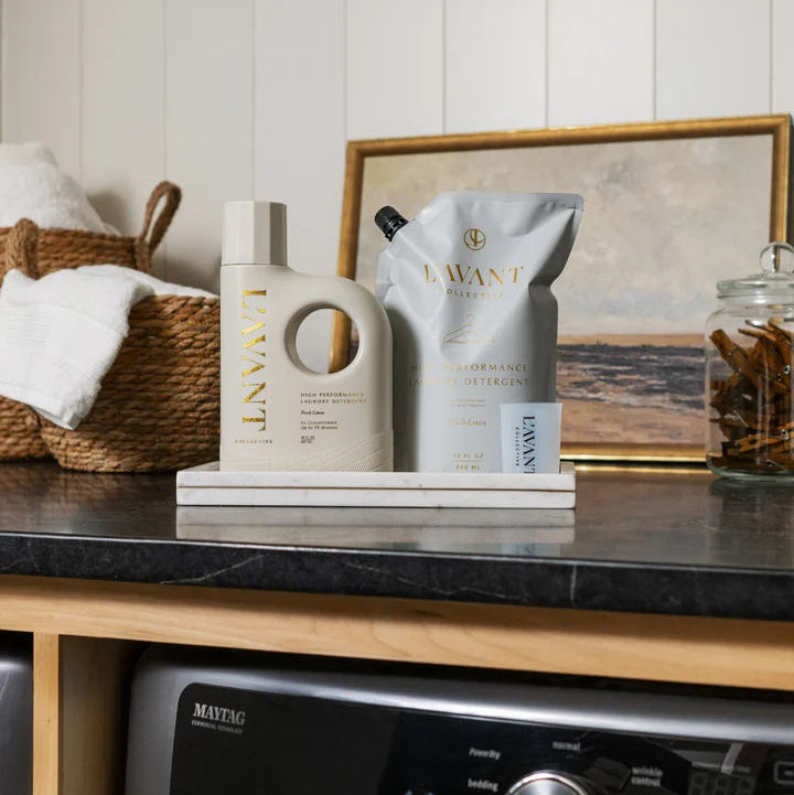 L’AVANT Collective laundry detergent bottle and Fresh Linen refill pouch displayed on marble tray in laundry room